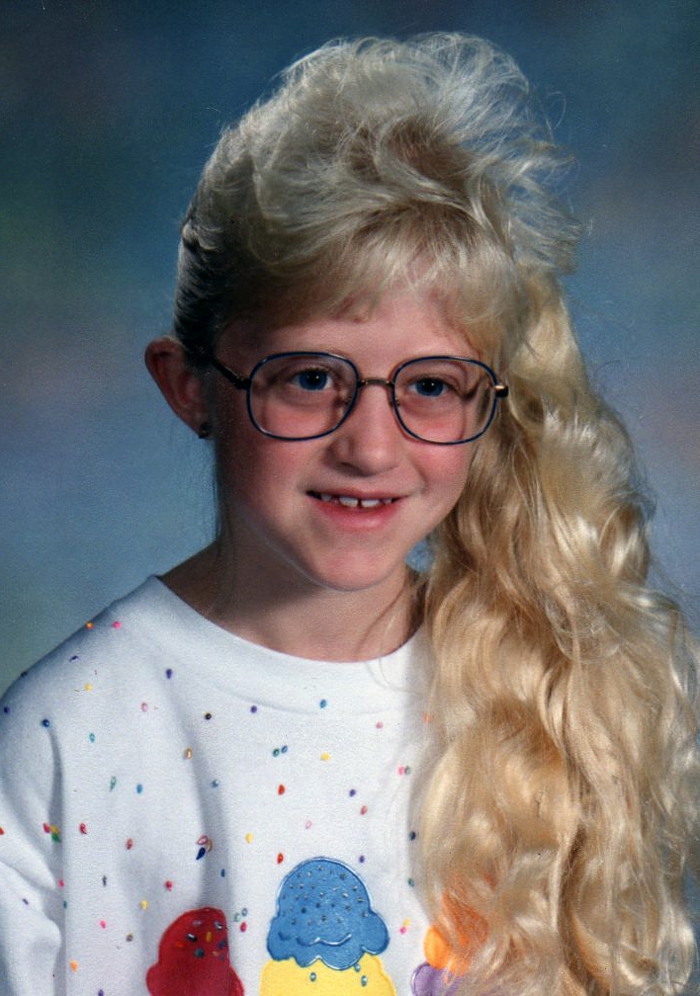 young blonde girl with big eyeglasses, feathered bangs and a long wavy side ponytail, wearing white jumper decorated with colorful ice creams and sprinkles
