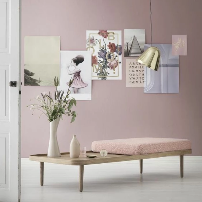 color schemes for living rooms, white open door, light wooden table with pink cushion short legs, pink wall with seven colorful posters, white floor vase and decorative bottle