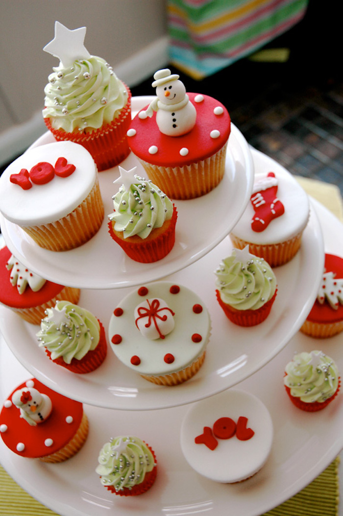 cupcakes of different sizes, with white and red fondant icing and pale green creamy frosting, on several differently sized white stacked plates
