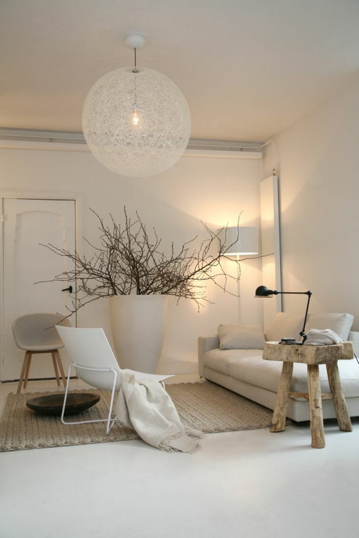 living room paint colors, cream colored walls, white sofa and chair, small rough wooden chair, big white vase with dry tree branches, cream chunky rug and cream chair