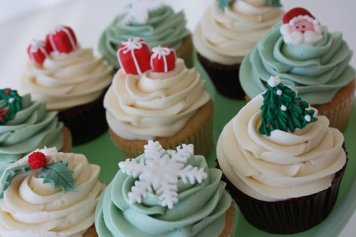 batch of chocolate and vanilla cupcakes, pale green and yellow icing, decorated with white, green and red fondant shapes