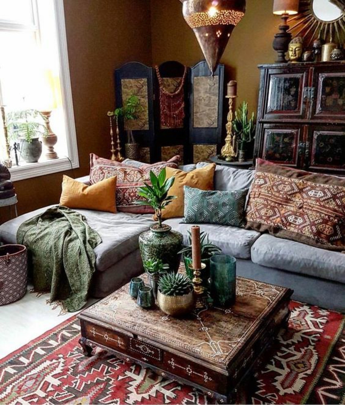 living room color schemes, brown walls and a colorful persian carpet, pale grey sofa, yellow and patterned cushions, eastern wooden furniture and ornaments, plants lamps and candles