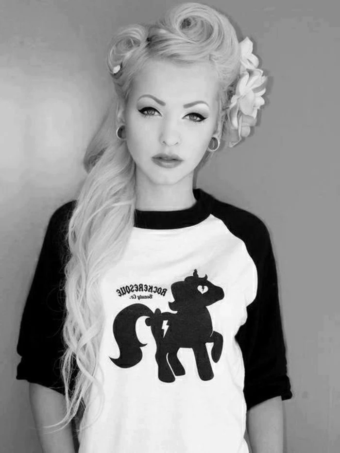 pinned up hairstyles for long hair, platinum blonde young woman with heavy make up and flesh earrings, three fake flowers in hair, black and white pony t-shirt