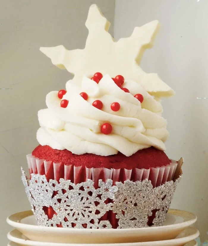 close up of red velvet cupcake with white frosting, decorated with big white snowflake shape and red pearls