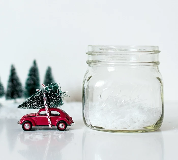 homemade christmas gift ideas, empty clear bell jar, near a red car toy with miniature christmas tree tied on its roof, with red and white string