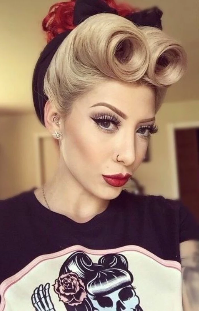 pouting blonde woman with blonde hair, styled in victory rolls with black hair bow, curly hair bun dyed in red, heavy make up with big fake lashes and black eyeliner