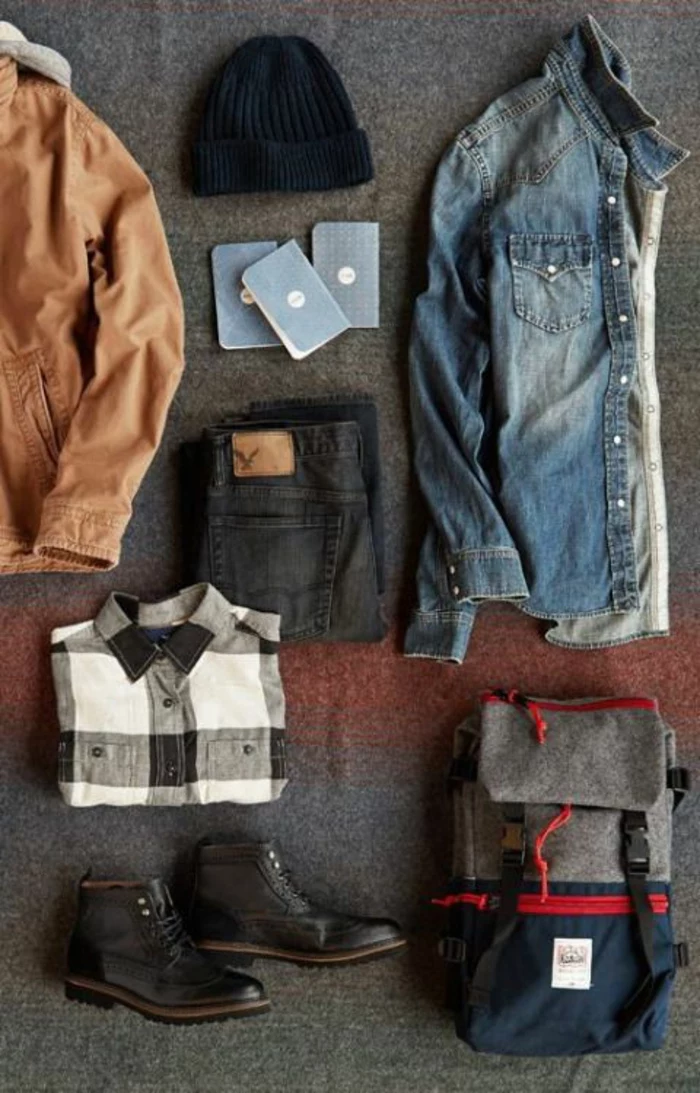 business casual outfits, light brown men's jacket, near folded black jeans, folded black white and gray chequered shirt, a pair of black lace up ankle boots, navy blue grey and red backpack, folded denim shirt and navy beanie hat
