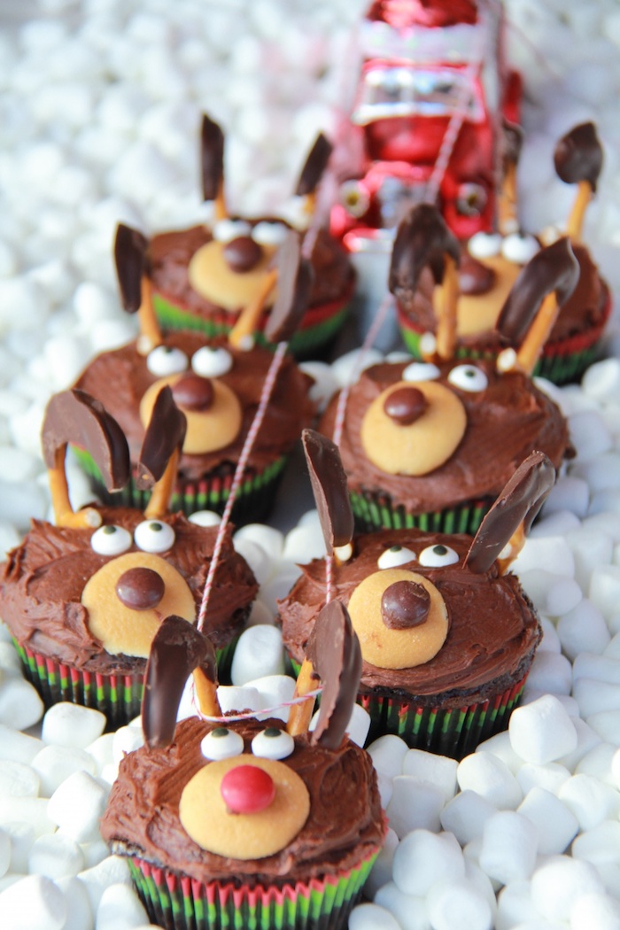 chocolate cupcakes images, seven cupcakes with chocolate frosting, made to look like santa's deer, with biscuits and candies, tied with red and white string to red toy car