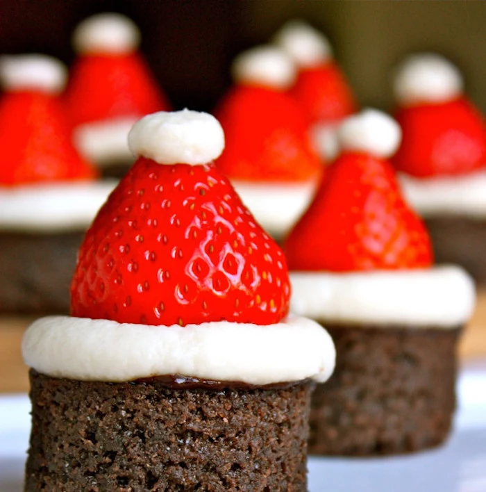 a batch of brownies, decorated with little santa hats, made from strawberries and cream