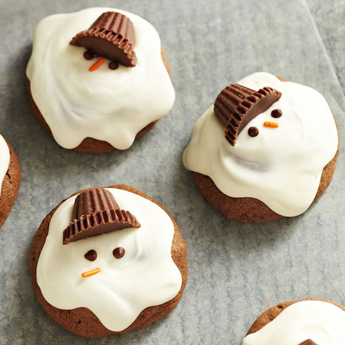 several cupcakes with white frosting, made to look like melting snowmen, with chocolate candies for caps