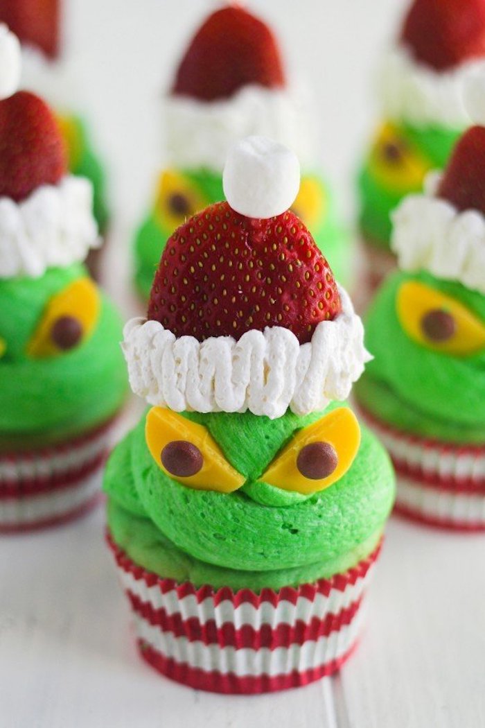 holiday cupcakes, a batch of cupcakes with acid green frosting, decorated with strawberries and cream, yellow and chocolate candies 