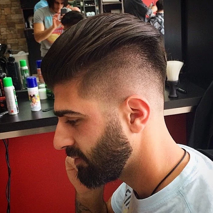 slicked back undercut, middle eastern man with beard and mustache, dark hair trimmed very short on sides and long, slicked back on top, facing sideways and wearing light t-shirt