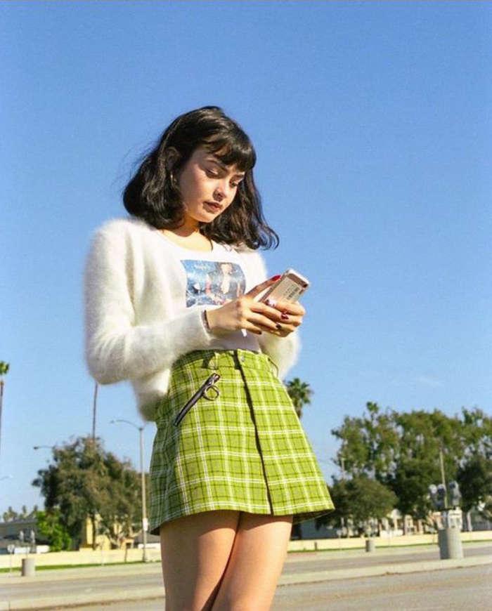 throwback thursday outfits, girl with shoulder-length black hair and bangs, wearing a short tartan lime green mini skirt, white t-shirt and a white fluffy cardigan