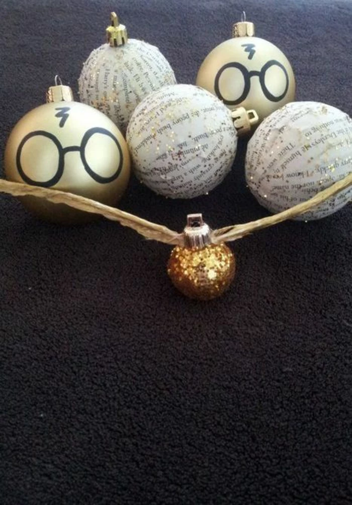 three christmas tree ornaments decorated with golden book pages and glitter and, two decorations with eyeglasses and a lightning scar drawn on them, one glittering golden ornament with wings