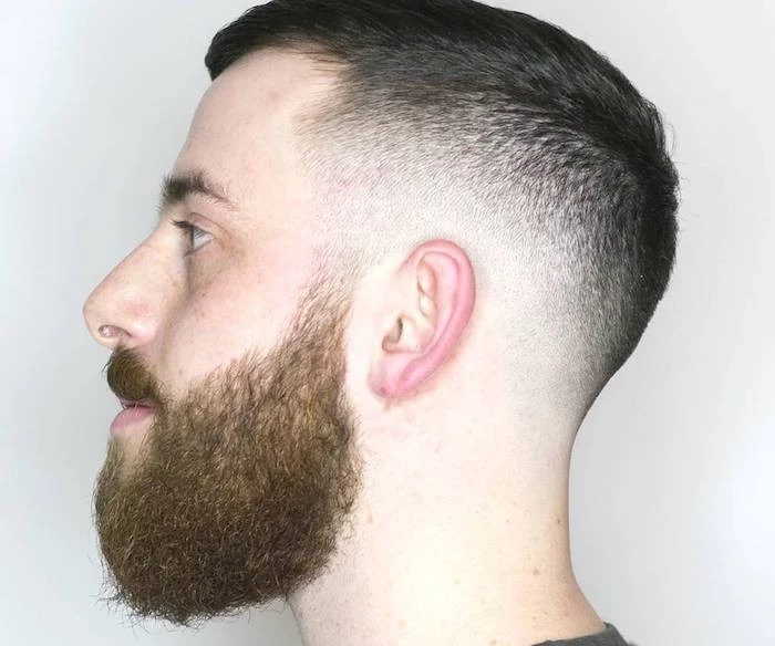 undercut hairstyle men, close up of a pale man in profile, beard and mustache, short hair on sides and slightly longer on top