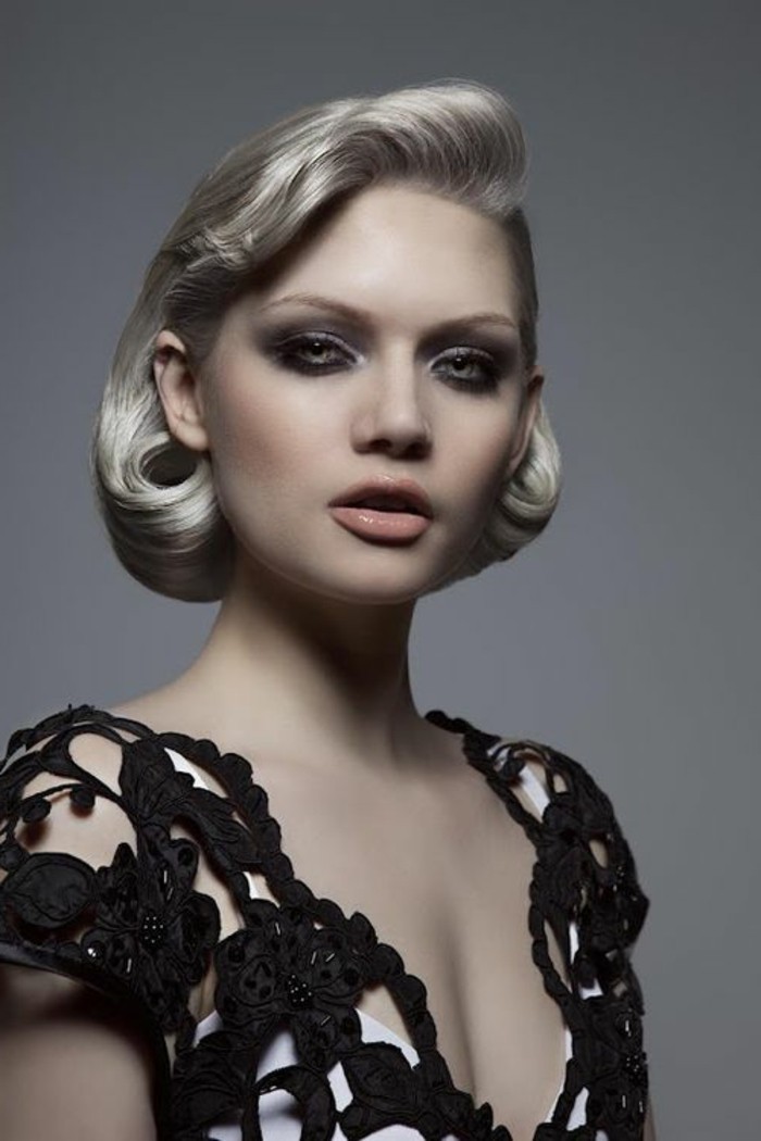 platinum blonde woman with short hair in 1940's style, pale nude lipstick and heavy eye make up, with black eyeliner and mascara, black and white top and grey eyes