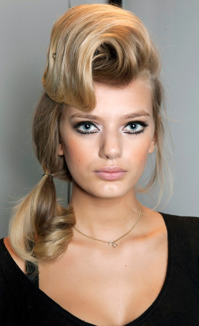 pinup style, close up of woman with avant-garde make up and hair, bold black eyeliner and fake eyelashes with mascara, nude-colored lipstick, big curled bangs and small curly pony tail