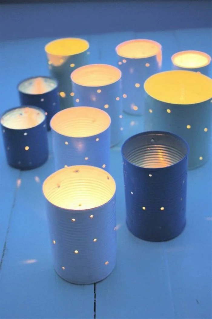 several luminaries made from cans in different sizes, painted in blue, with holes seeping light
