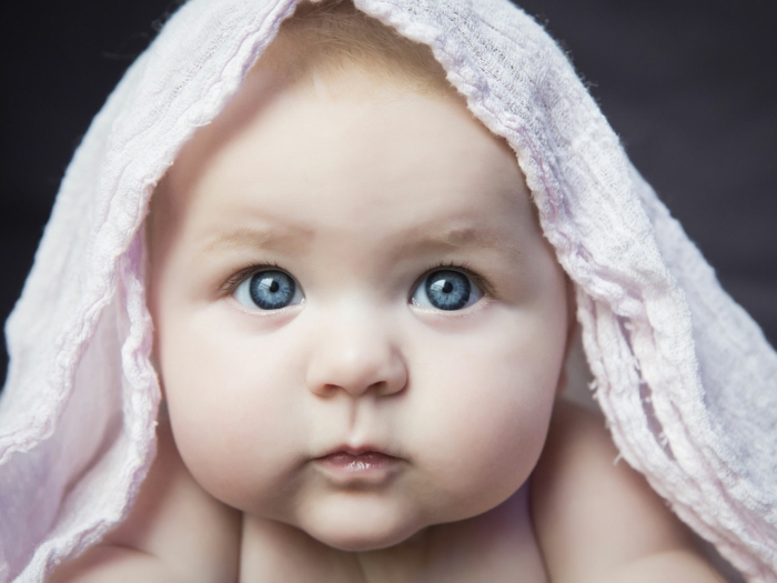 baby eye color, chubby blue-eyed baby with big cheeks, with a pale pink cloth over its head