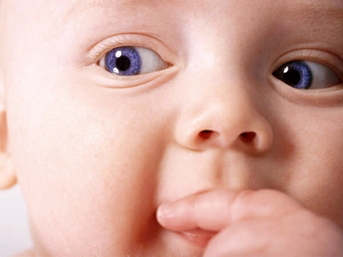 baby eye color, extreme close up of a small baby's face, with violet eyes, sucking its finger