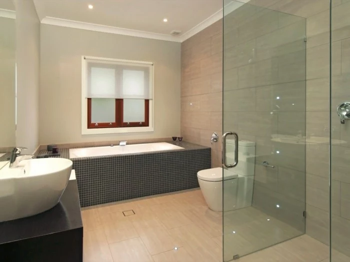 bathroom remodel, rectangular inbuilt bath, light wood flooring, white sink and toilet, glass shower cabin