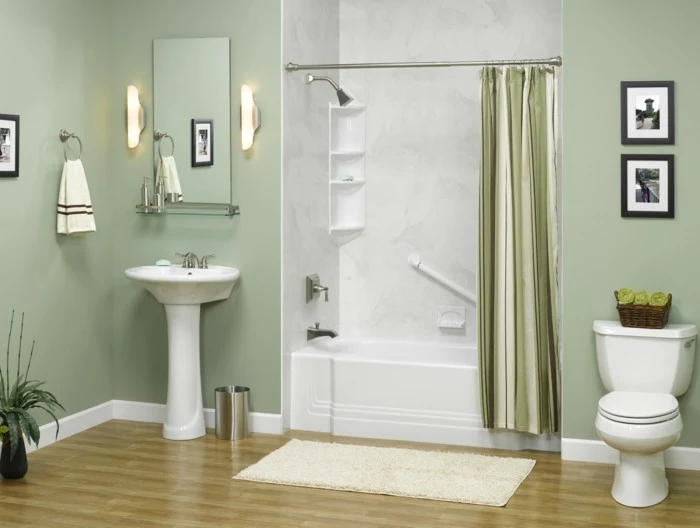 bathroom remodel, pale green walls, white ceramic sink and toilet, mirror and two wall lamps, white and grey open plan shower area with green curtain