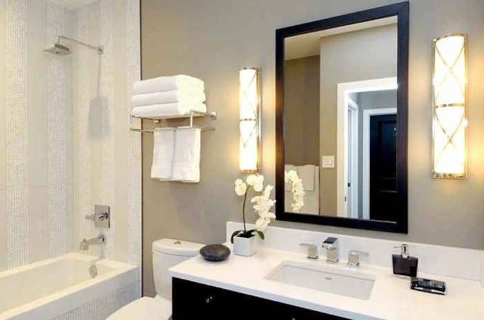 remodeling ideas, cream-colored wall with mirror in a dark frame, black cupboard with white sink, white and cream shower and bath area