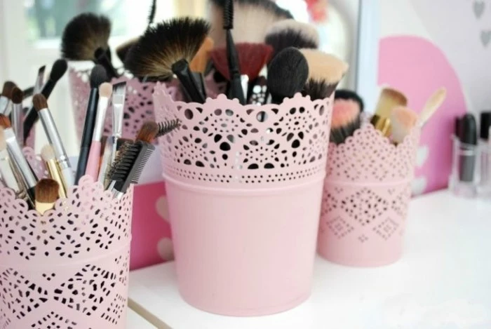 cool gifts for teens, three ornate pots painted in pale pastel pink, containing a wide variety of make-up brushes
