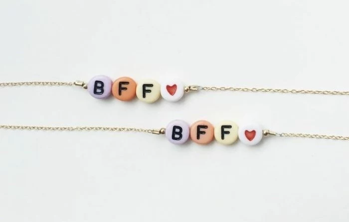 gifts for best friends, close-up of two bracelets, thin gold-colored chains, decorated with colorful pebbles, with the letters BFF and a heart