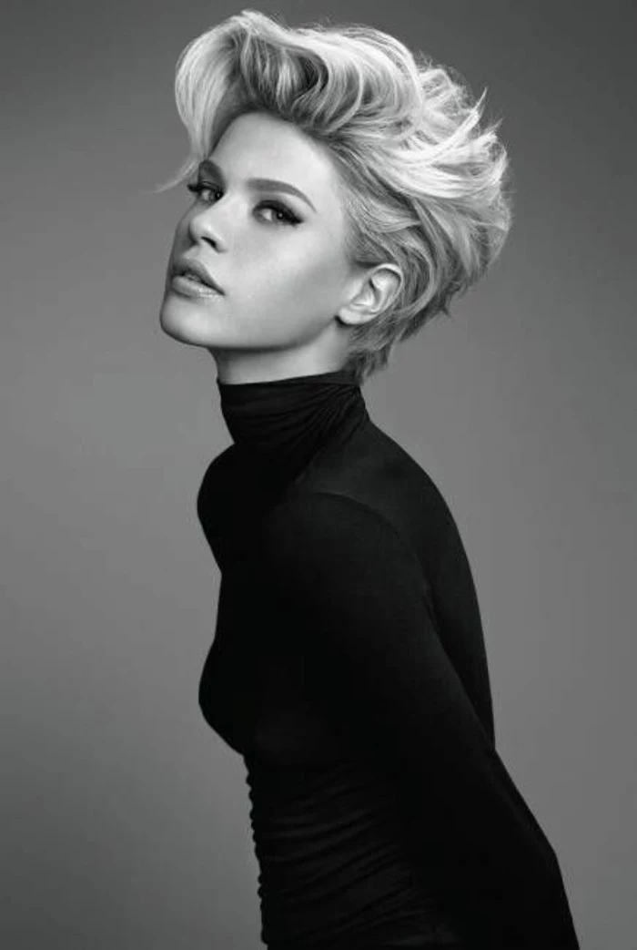 black and white photo of a woman, short gelled up blonde hair, black turtleneck and eyeliner