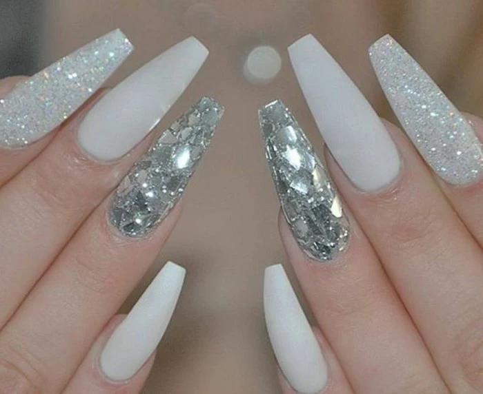 rhinestone nail designs, eight very sharp nails, painted with white nail polish, two nails covered in white glitter, another two decorated with shiny glittering shards