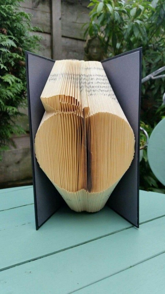 book folding, apple shape made from folded pages, inside an open book, with dark grey and black hard covers