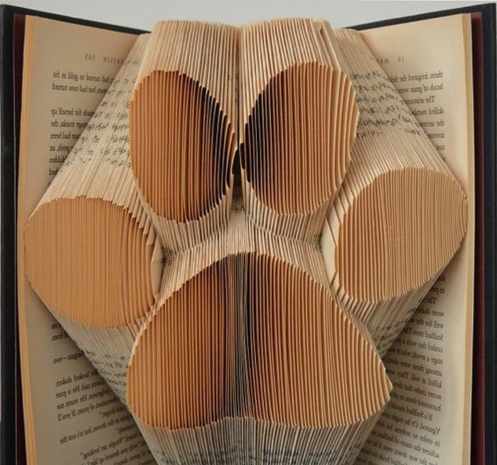 book folding art, giant paw print, made from folded pages, inside an open vintage book, with dark hard covers