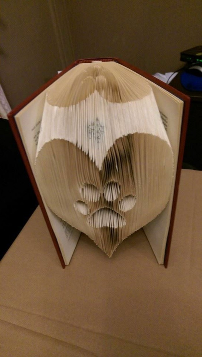 book folding art, heart shape with paw print, made from folded pages, inside an open book, with dark red hard covers