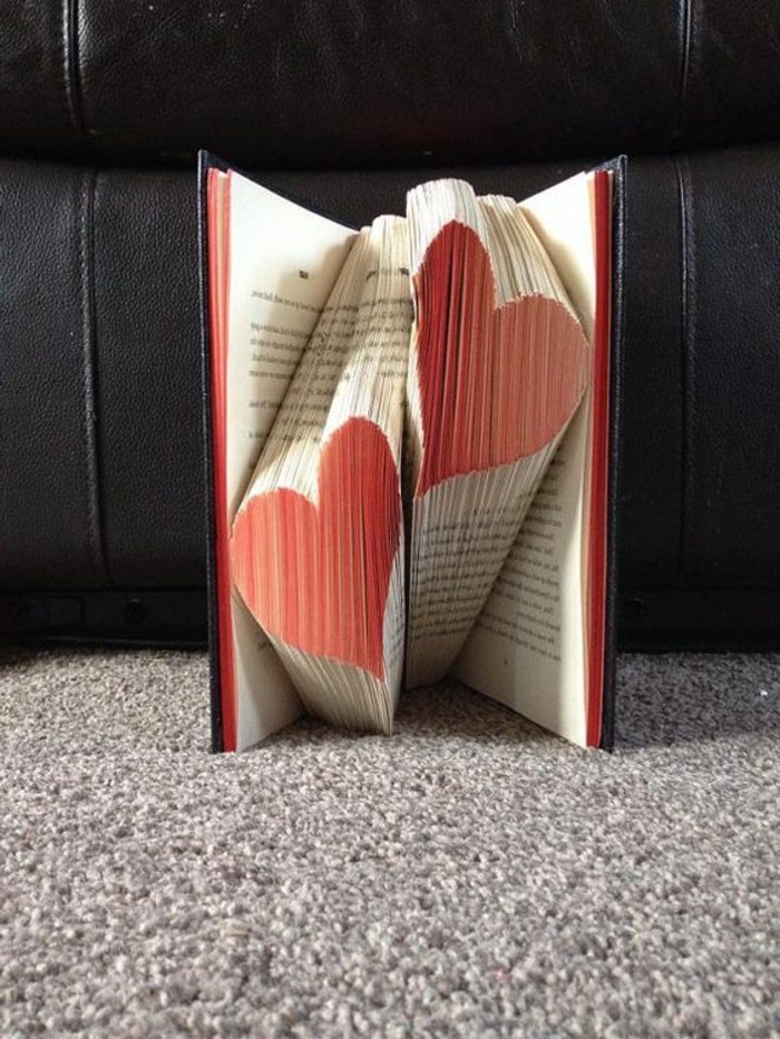 book folding art, two hearts made from folded pages, and painted red, inside an open book with black hard covers