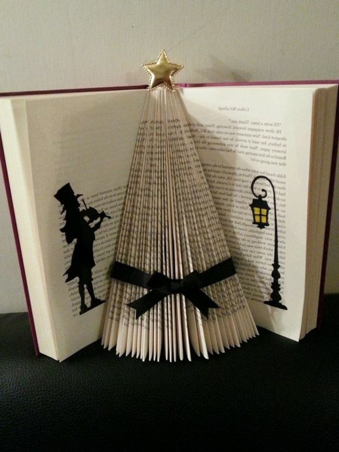 book folding, open book with red covers, containing Christmas tree shape, made from folded pages, decorated with a black ribbon, and shiny gold star, black silhouette shapes, drawn in marker on nearby pages