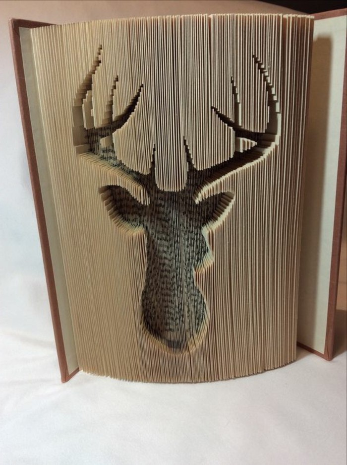 book folding patterns, semi-opened book, with hard brown covers, an elk-head shape carved into its pages