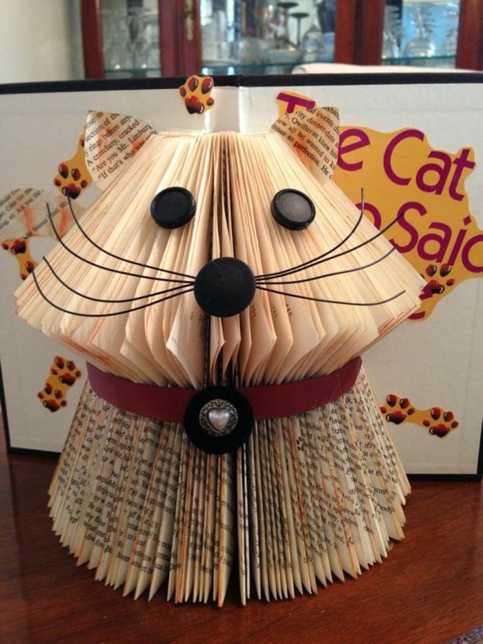 book folding patterns, small cat ornament, made from cut and folded book pages, decorated with round black plastic buttons, wire whiskers and a red collar