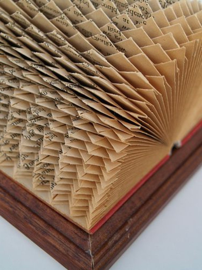 book folding patterns, vintage book with red covers, placed in wooden frame, opened to reveal intricate geometrical pattern, made from folded pages