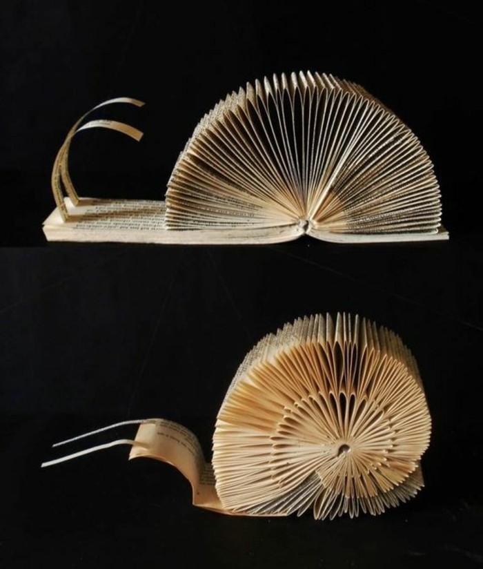 book folding patterns, two snail decorations, made from cut and folded book pages, placed on a black background