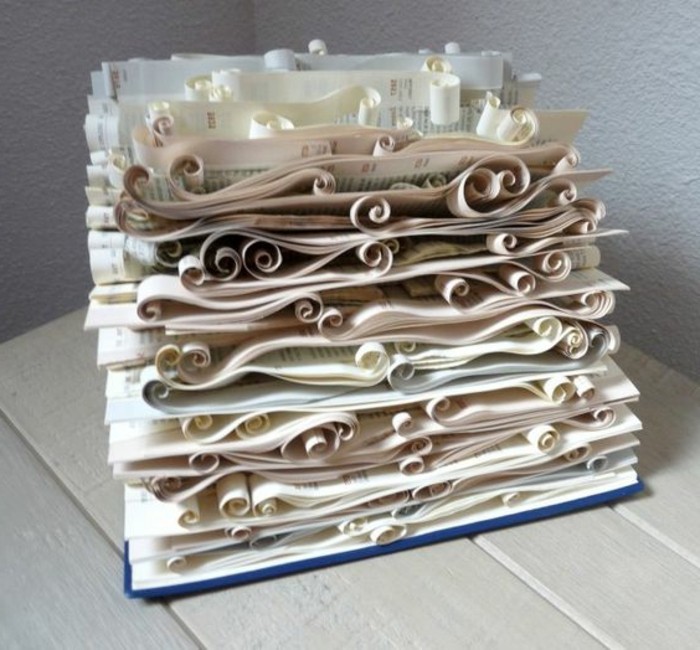 opened book with blue hard covers, containing many pages, ornately cut and folded into wavy curled shapes