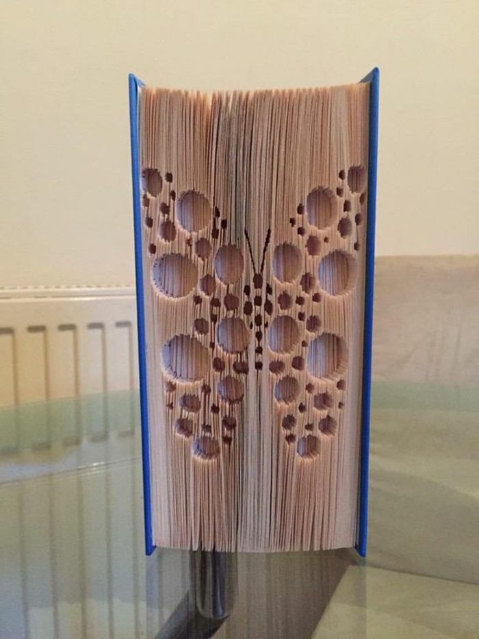 closed book with hard blue covers, a butterfly made from geometric shapes, carved into its pages