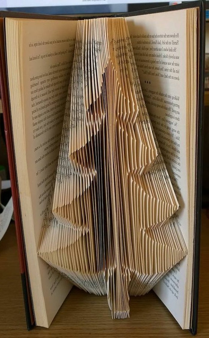 christmas tree shape made from folded pages, inside an open vintage book, with yellowy pages, and brown hard covers