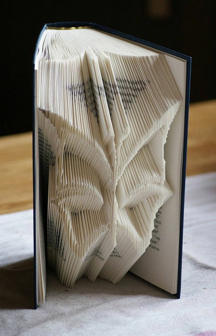 bookfolding, butterfly shape made from folded pages, inside an open book, with dark blue hard covers