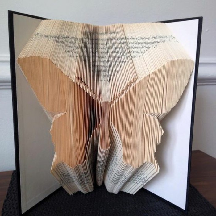 book folding, symmetrical butterfly shape, made from folded pages, inside an open book, with black and white hard covers