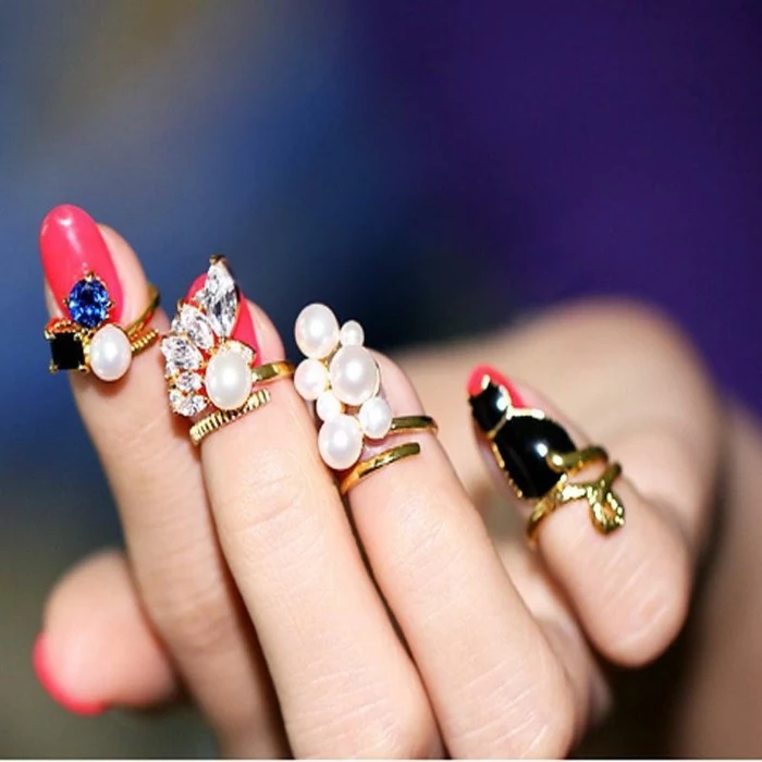 nails with rhinestones, hand with hot pink nails, small gold rings with pearls on fingertips