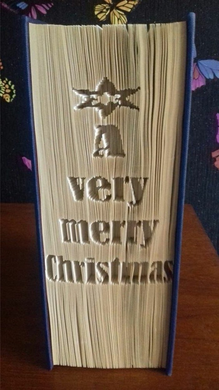 closed book with dark blue hard covers, a star and the phrase a very merry christmas, carved into its pages