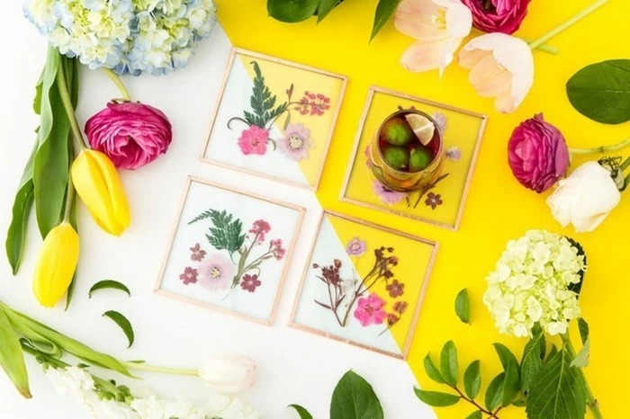 best friend birthday gifts, white and yellow table, containing four glass coasters with pressed flowers, surrounded by fresh tulips and hydrangeas