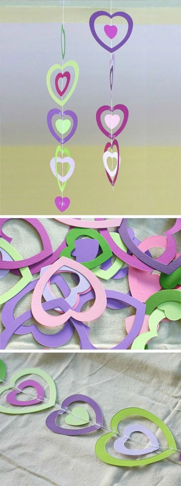 two garlands made from paper hearts, in different shades of pink, green and violet, attached together with white string and tape, close up of the garlands