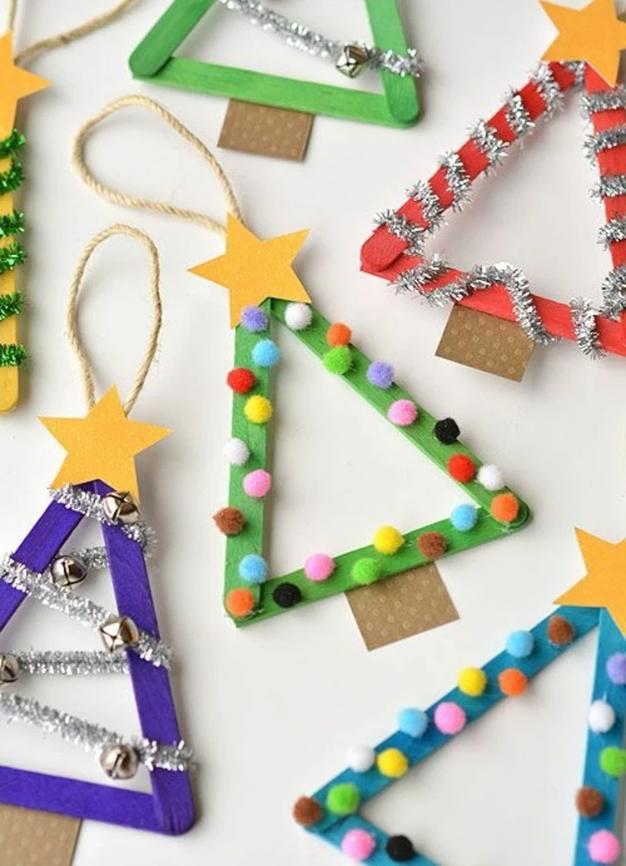 diys for your room, several christmas tree triangular shapes, made from ice cream sticks in different colors, decorated with yellow paper stars, colorful pom poms and silver garlands 